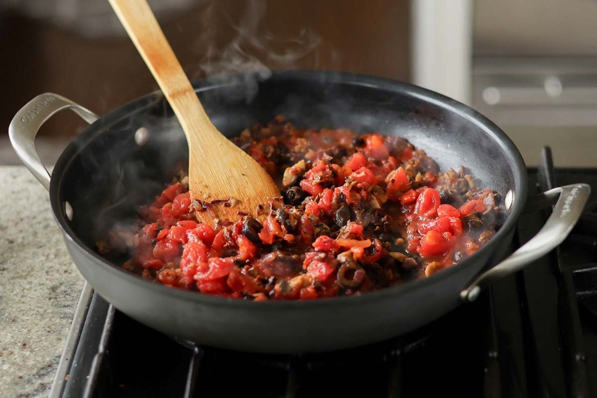 adding chopped tomato to the pan