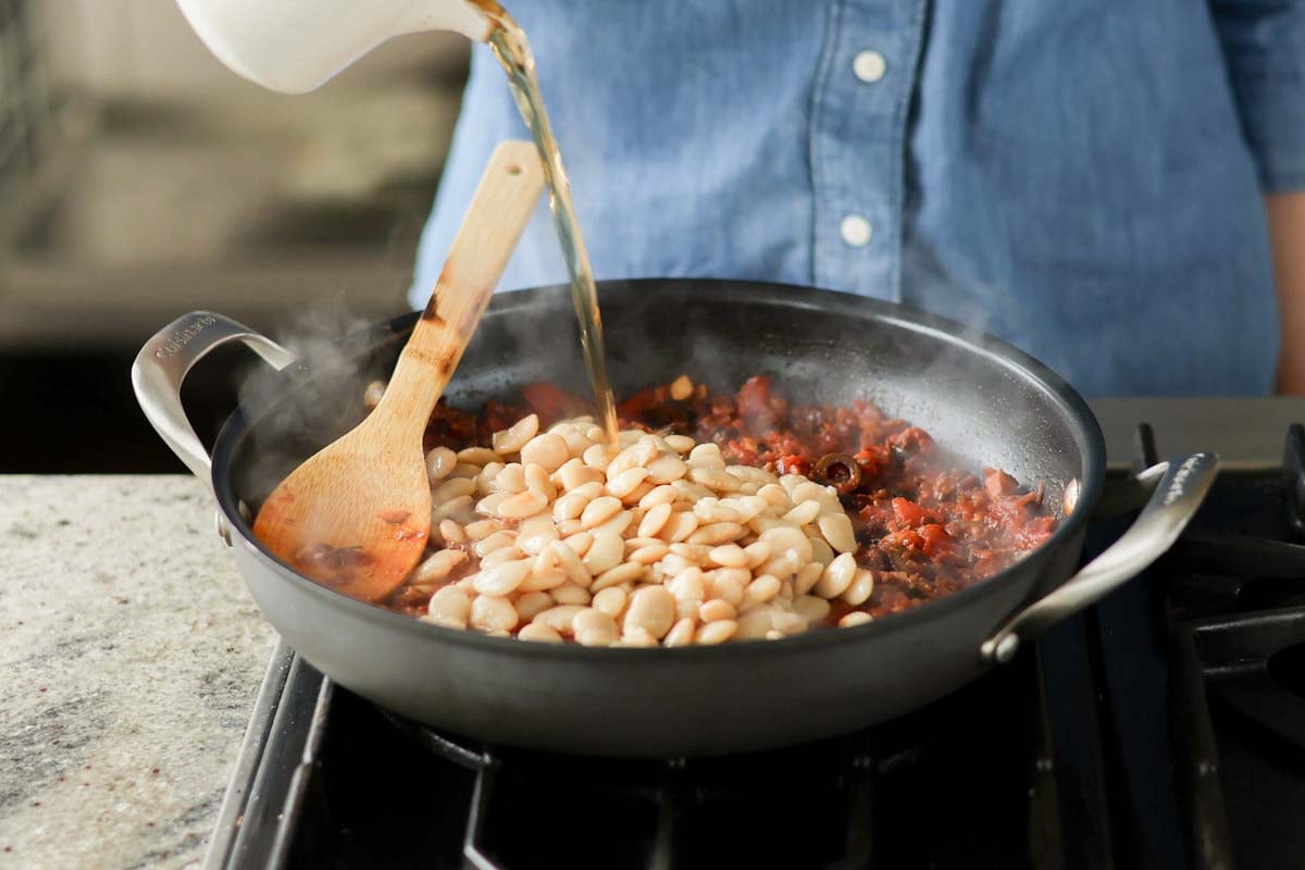 adding butter beans and water to the pan