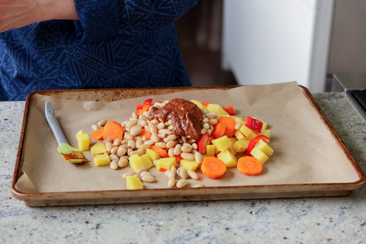 adding beans, veggies, and spice mixture to the sheet pan