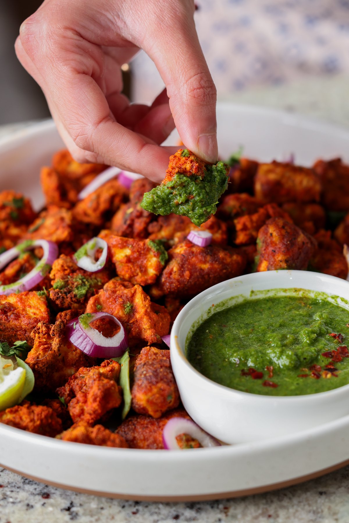 dipping a piece of tofu Koliwada into the mint chutney