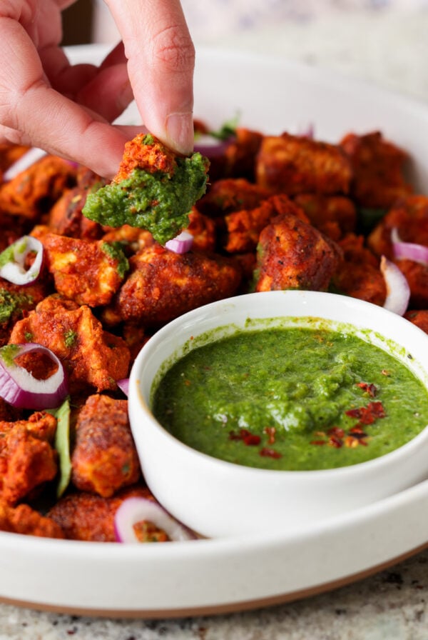 dipping a piece of tofu Koliwada into the mint chutney