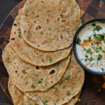 Indian flatbread on a cutting board with yogurt dip.