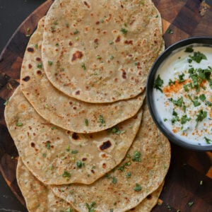 Indian flatbread on a cutting board with yogurt dip.