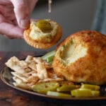 hand serving some jalapeño popper cheese ball onto a cracker