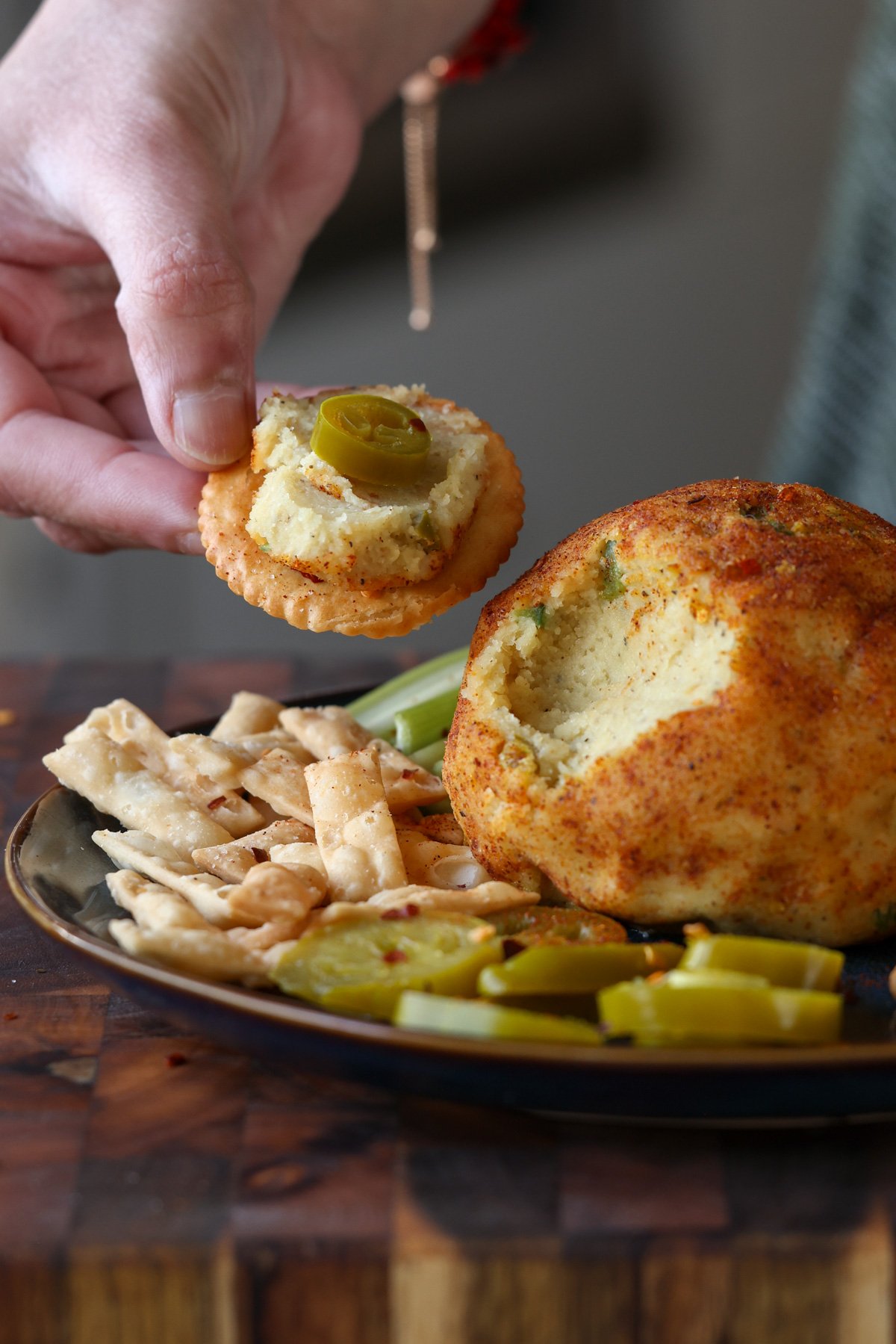hand serving some jalapeño popper cheese ball onto a cracker