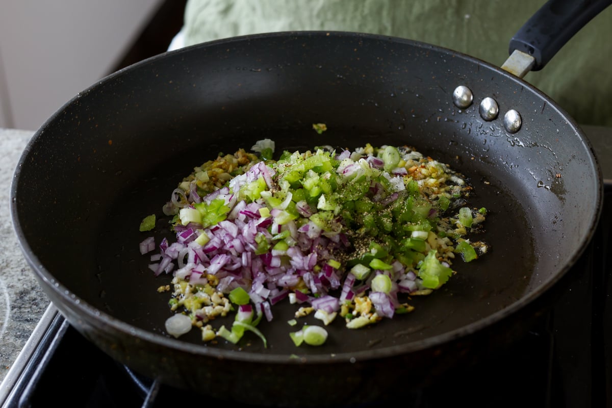 adding onions, chilis, and peppers to the pan