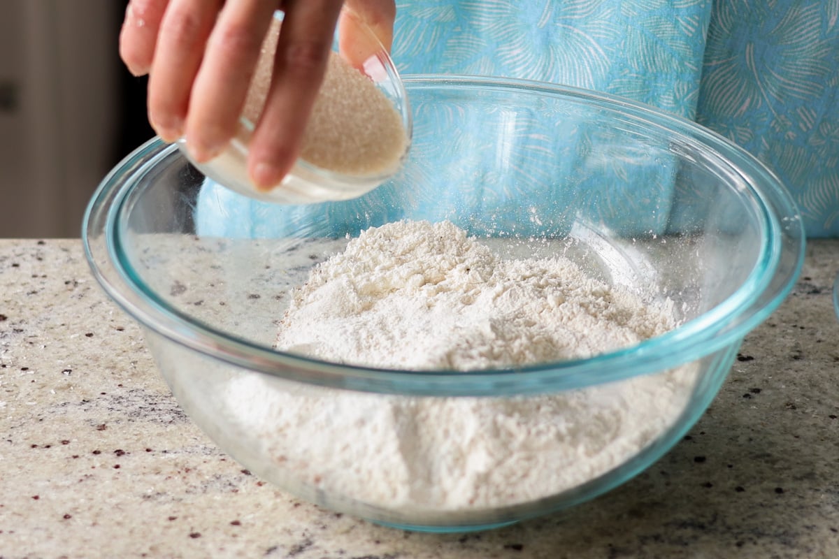 adding dry ingredients to a bowl