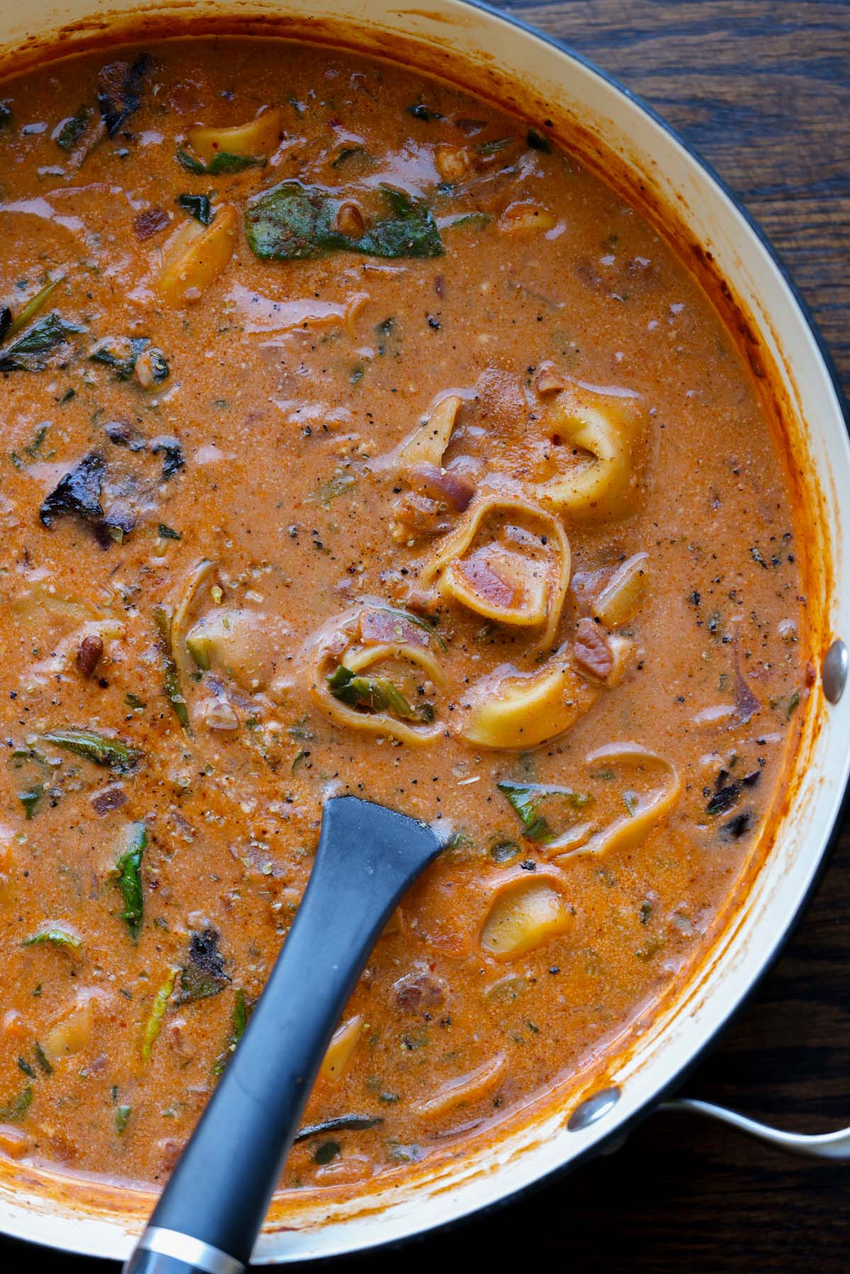 pan of tortellini soup with a ladle in it
