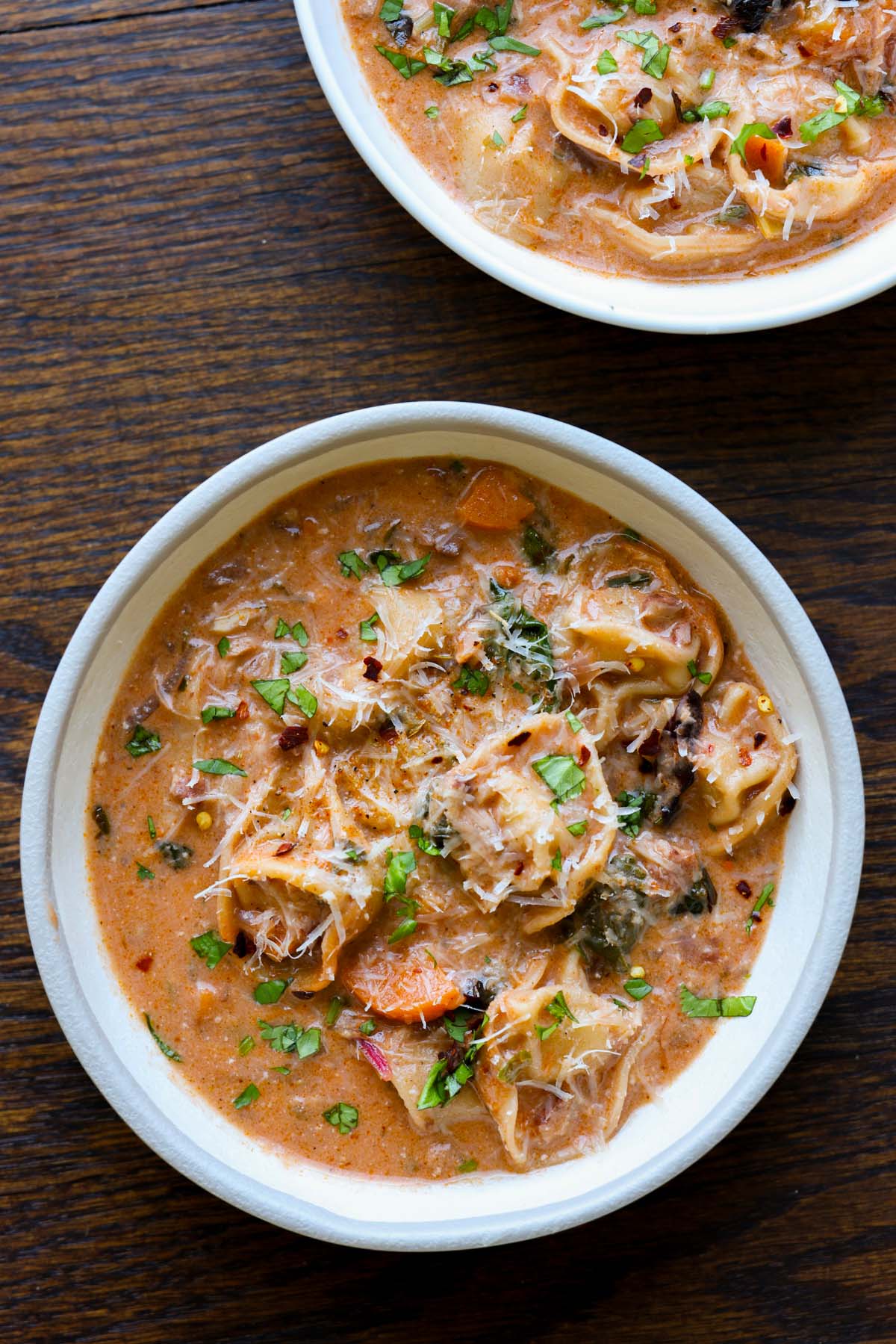 bowls of creamy tortellini soup on a wooden table