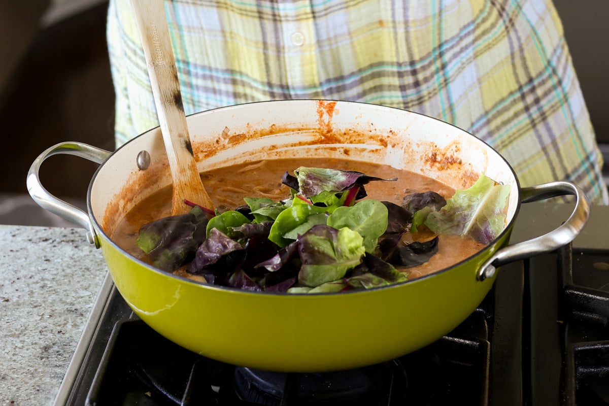 adding baby greens to the pan