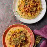 plates of harissa bean puree topped with roasted vegetables and baharat walnuts