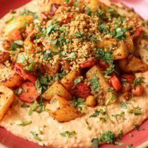 close-up of harissa bean puree topped with roasted vegetables and baharat walnuts