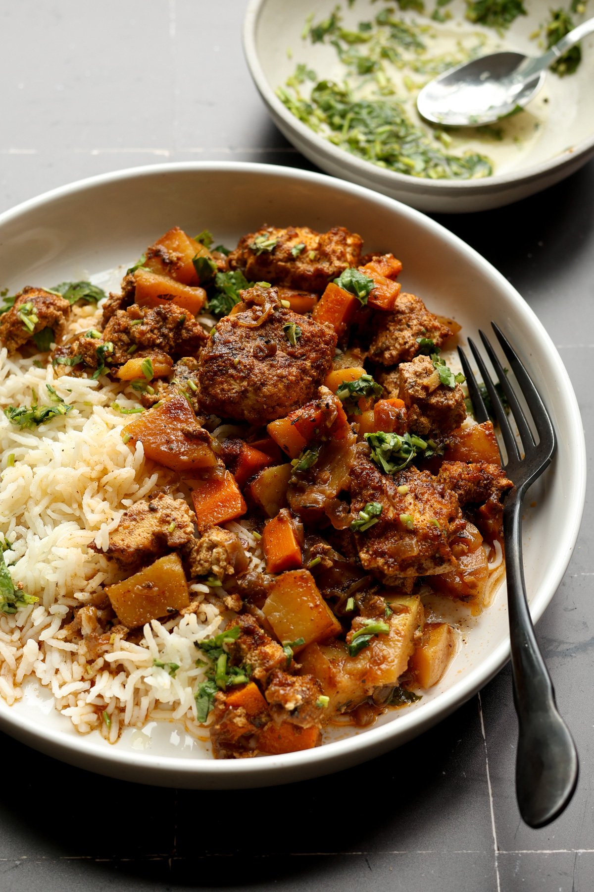braised tofu and veggies in a bowl with rice and herb sauce