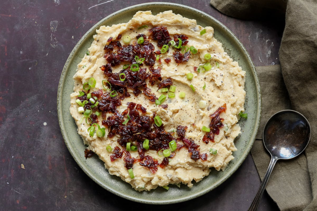 caramelized onion mashed potatoes on the plate topped with caramelized and green onions