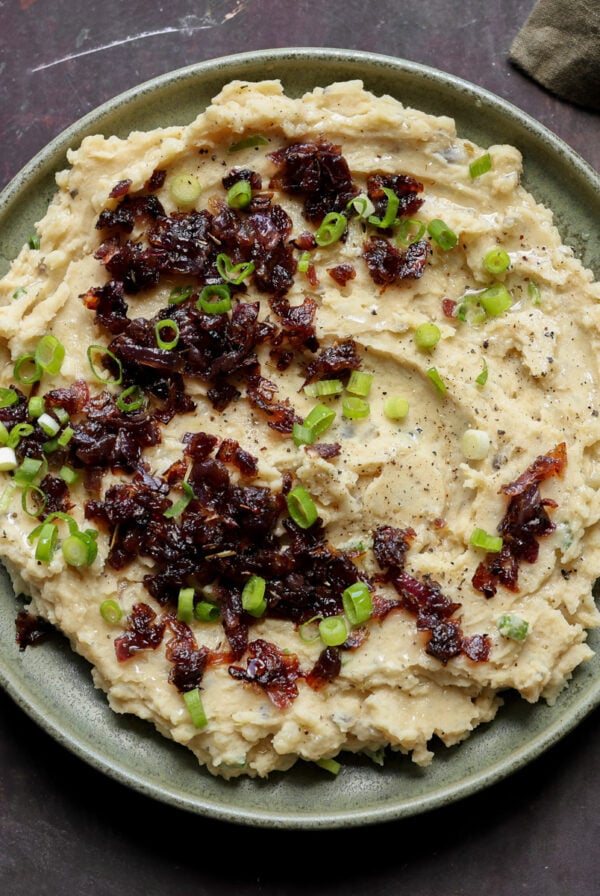 caramelized onion mashed potatoes on the plate topped with caramelized and green onions