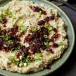 close-up of caramelized onion mashed potatoes on the plate topped with caramelized and green onions