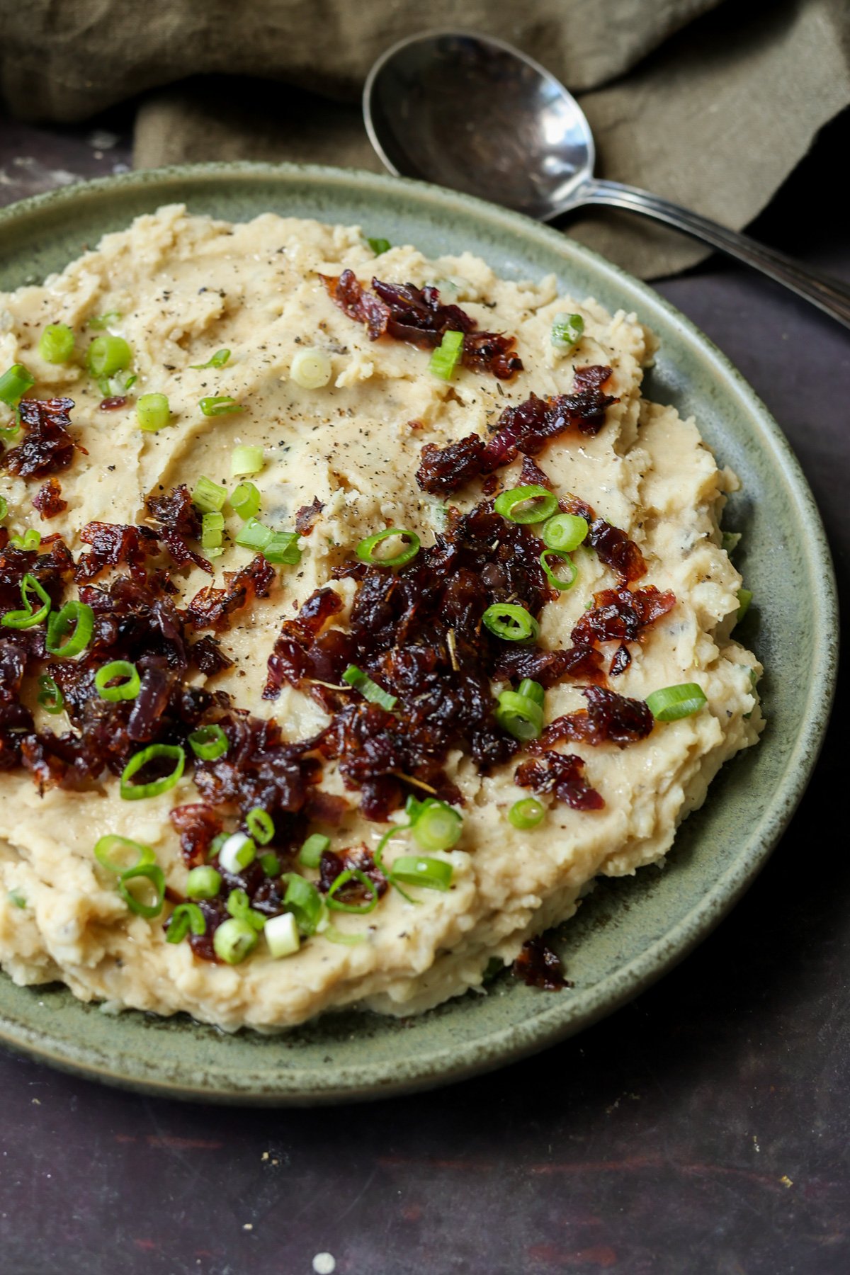 close-up of caramelized onion mashed potatoes on the plate topped with caramelized and green onions