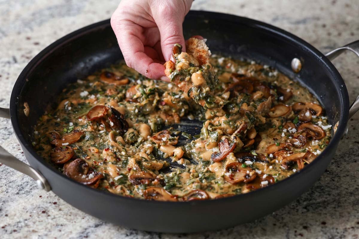 dipping bread into the spinach mushroom beans