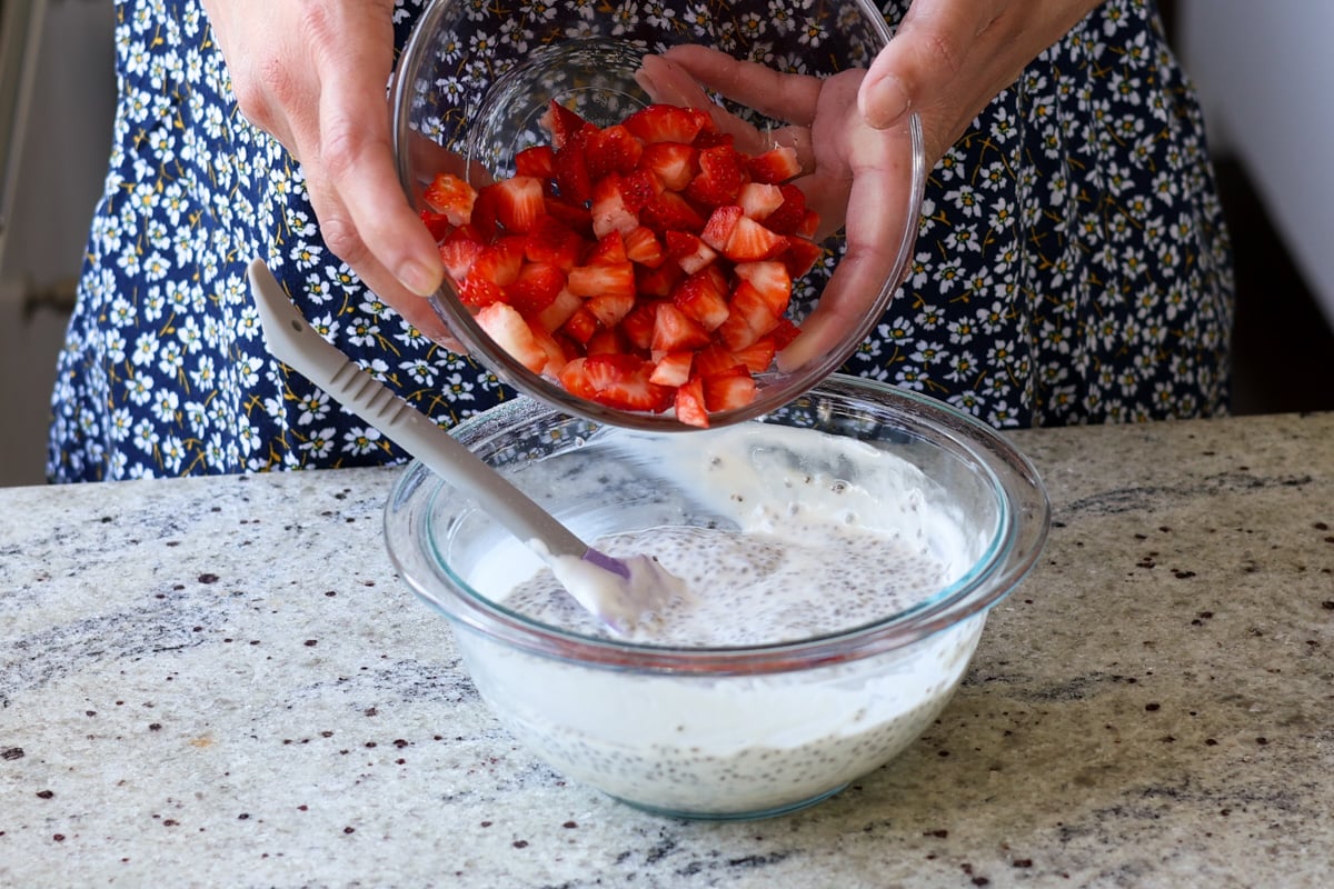 adding chopped strawberries to the chia seed pudding