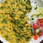 golden red lentil dal on a plate with kachumber salad