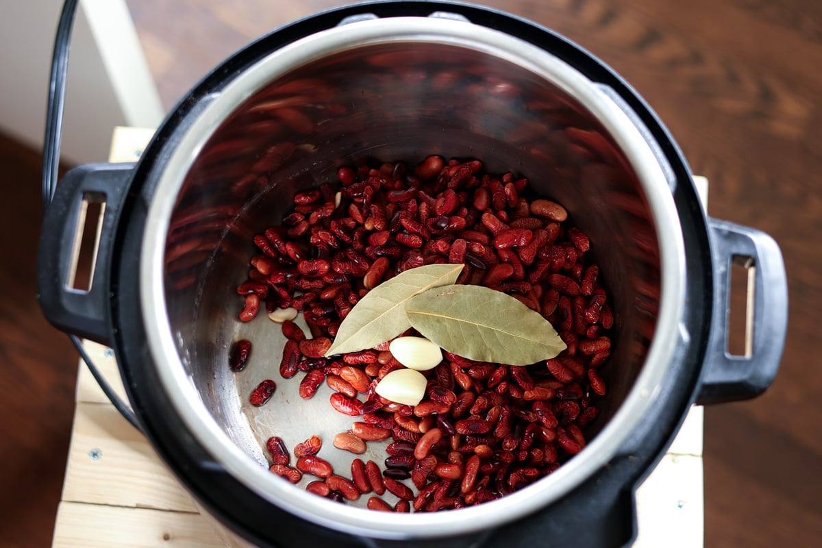 adding kidney. beans, garlic, and bay leaves to the Instant Pot