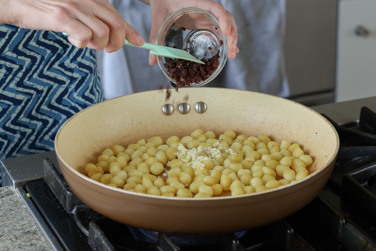 adding garlic and sun dried tomato to the pan