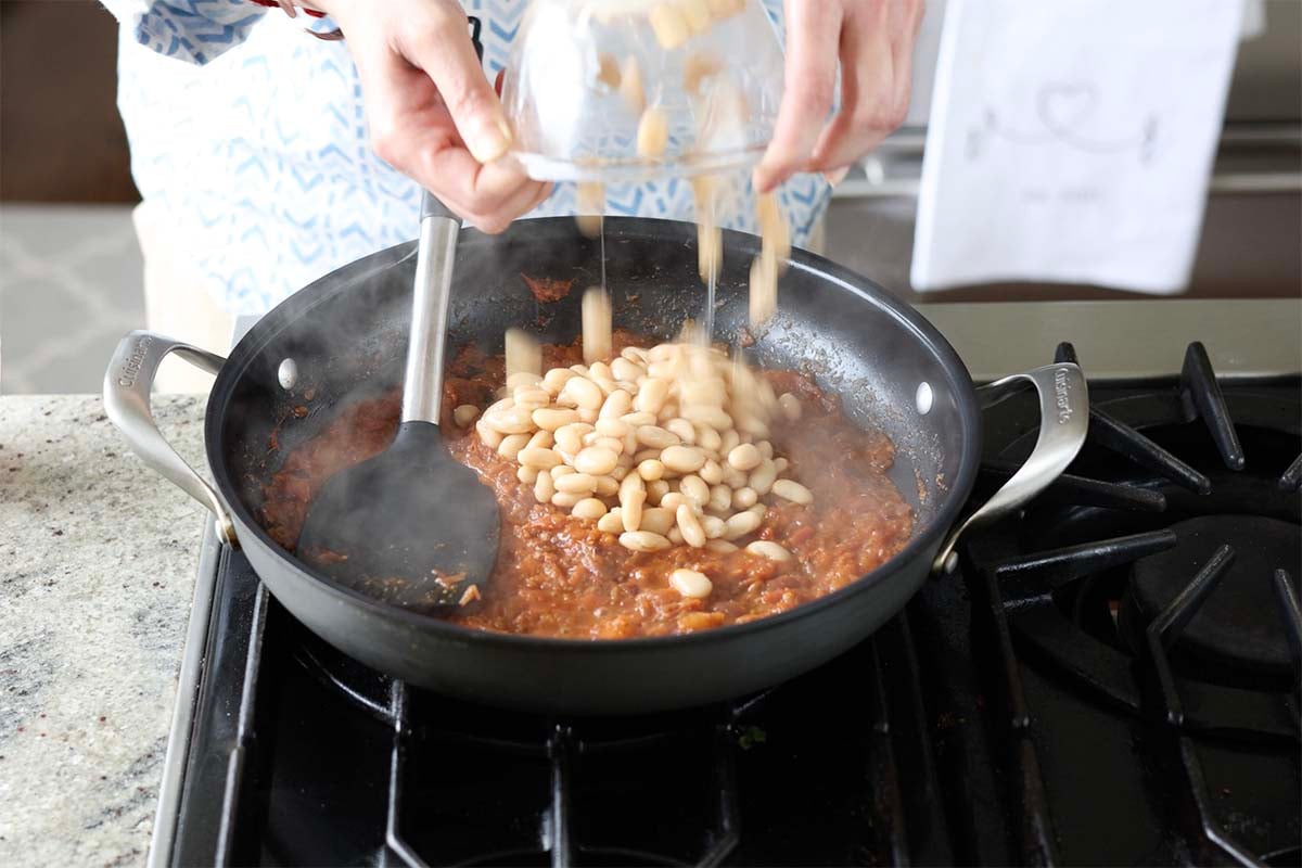 adding white beans to the pan