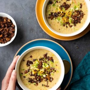 hands serving bowls of corn chowder