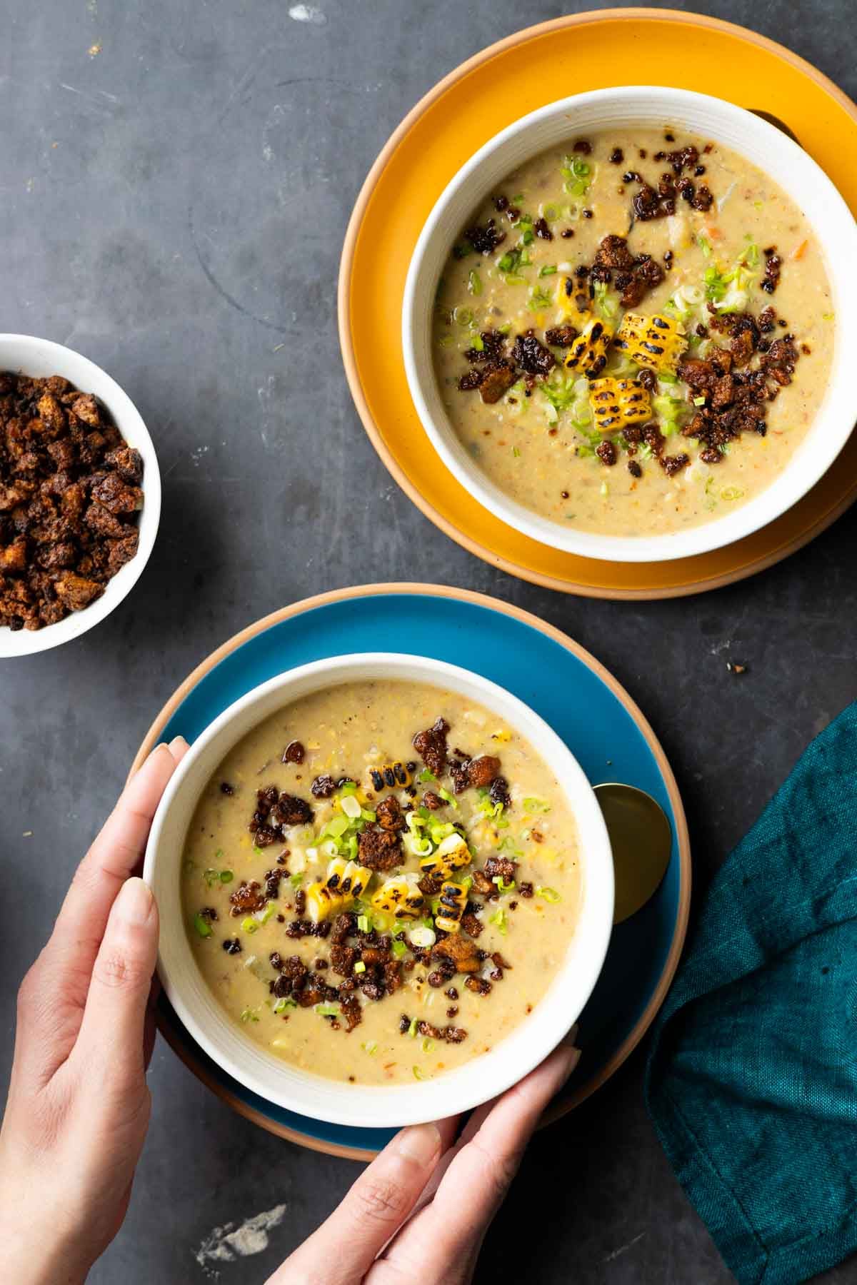 hands serving bowls of corn chowder