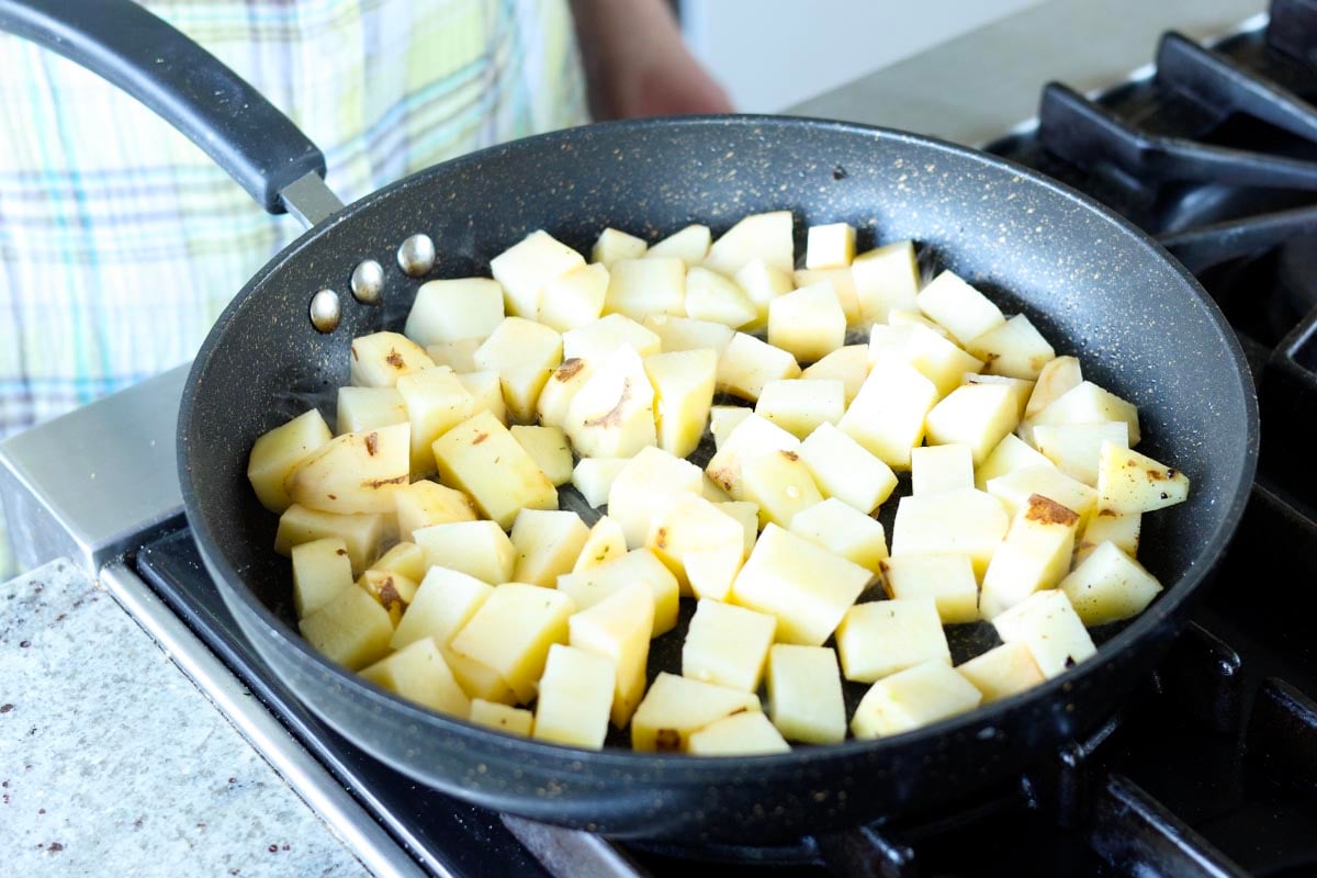 adding potatoes to the pan