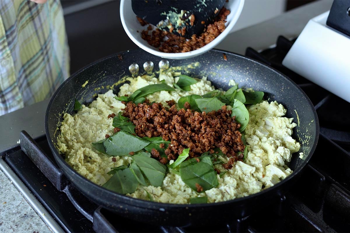 adding spinach and sausage to pan