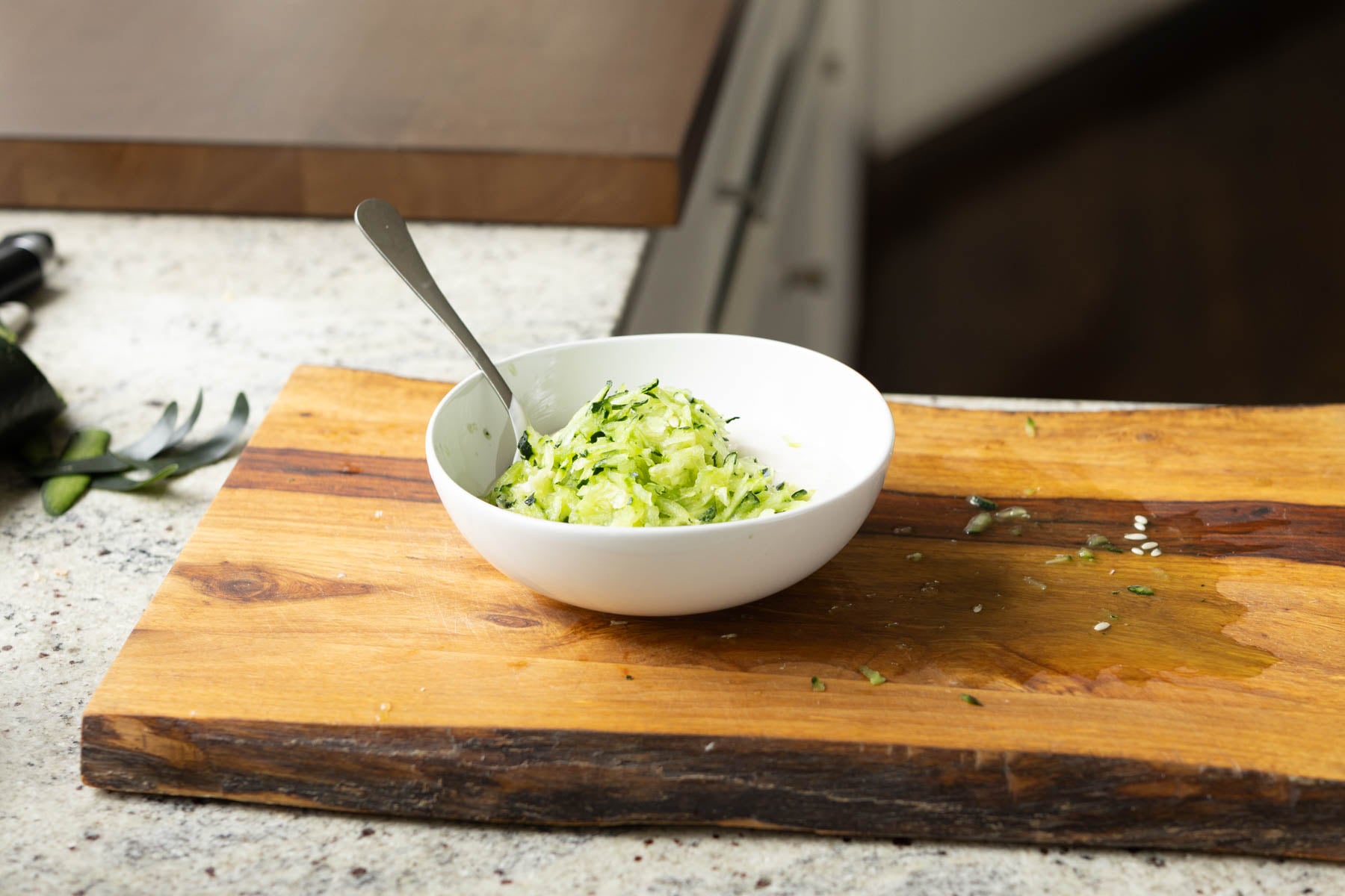 adding yogurt and grated cucumber to a bowl