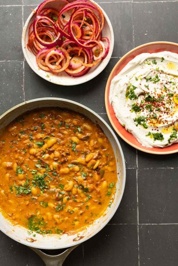 chili garlic beans, onion salad, and whipped tofu in bowls on a black table