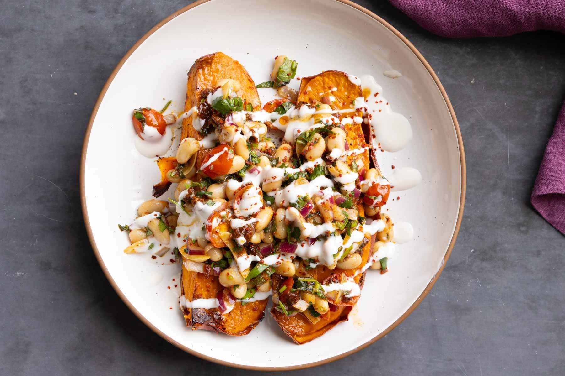 marinated white bean salad over sweet potatoes with creamy sauce on top