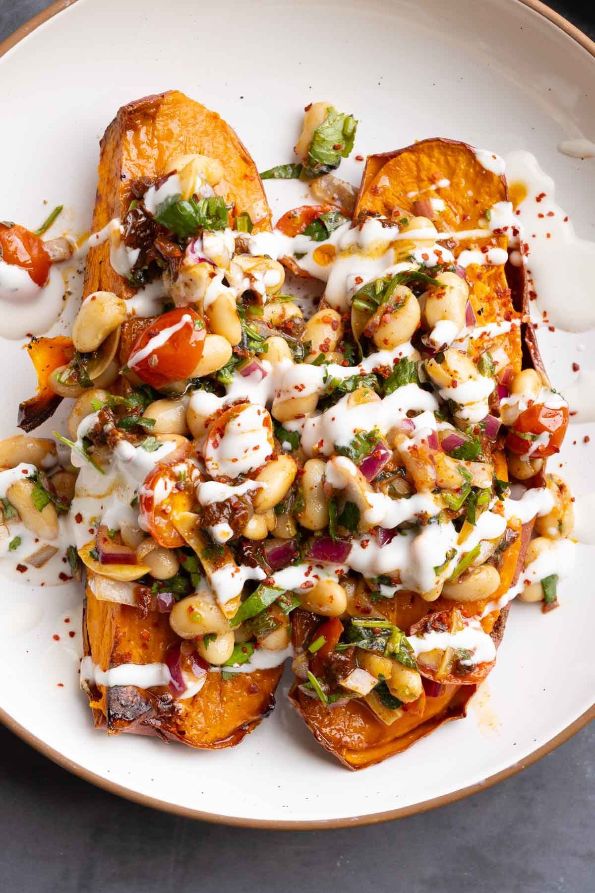 marinated white bean salad over sweet potatoes with creamy sauce on top