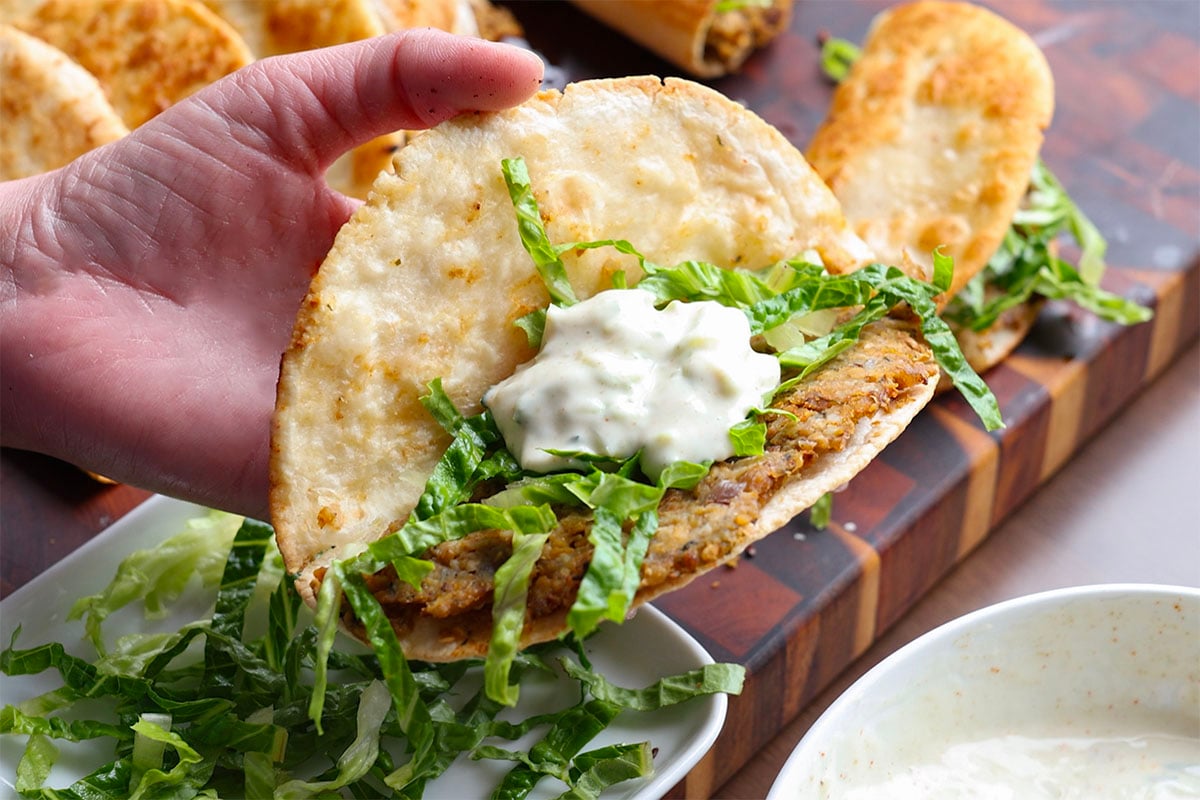 stuffing lettuce and raita into the paratha taco