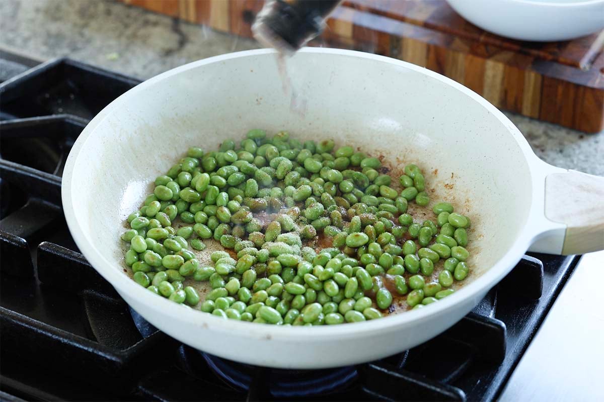 adding soy sauce and garlic powder to the edamame