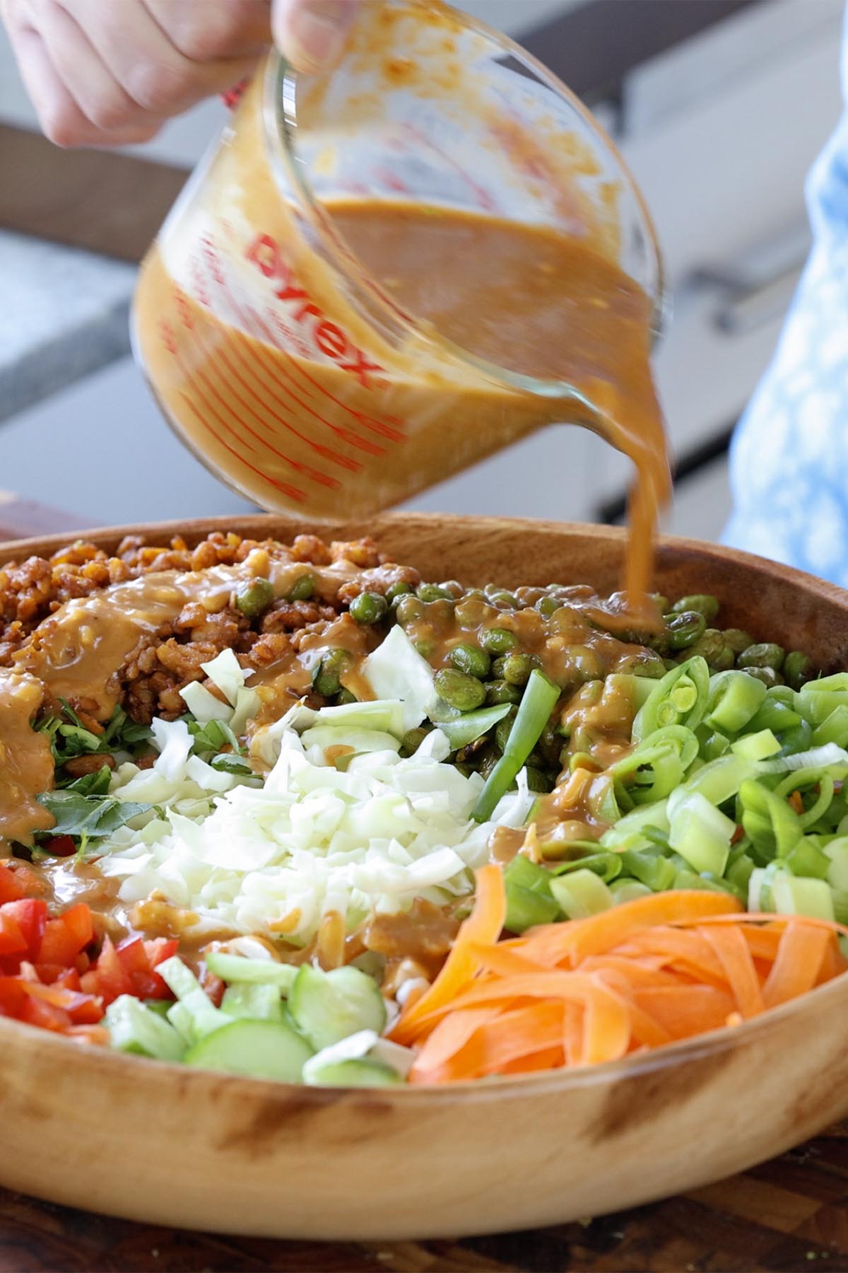 pouring the dressing onto the gochujang salad