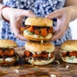 hands picking up a curry glazed tofu sandwich