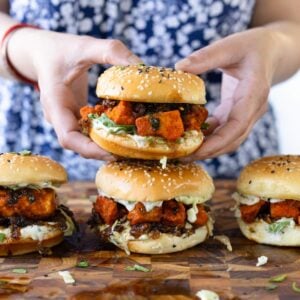 hands picking up a curry glazed tofu sandwich