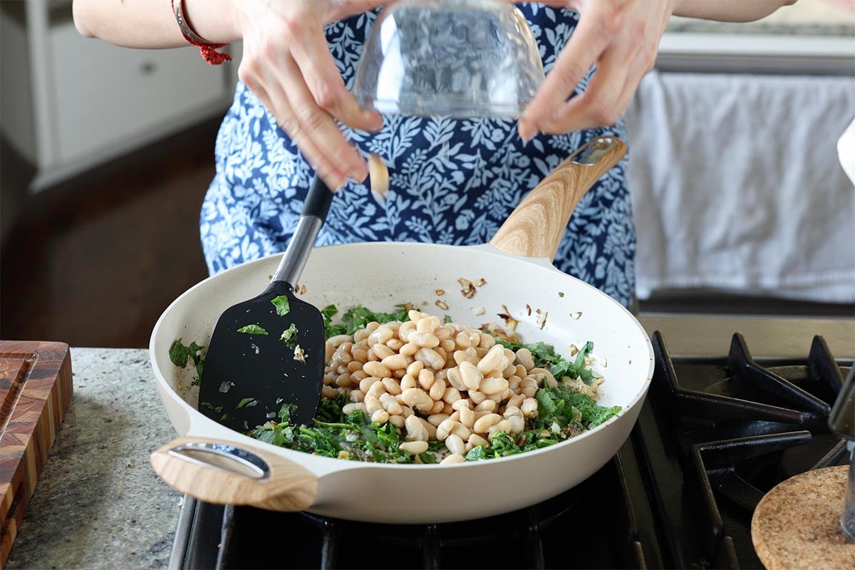 adding the white beans to the pan