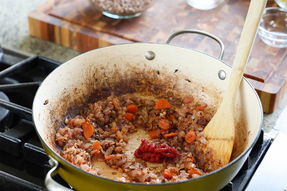 adding tomato paste to the pan