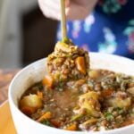 close-up of a spoon taking a bite of lentil potato soup