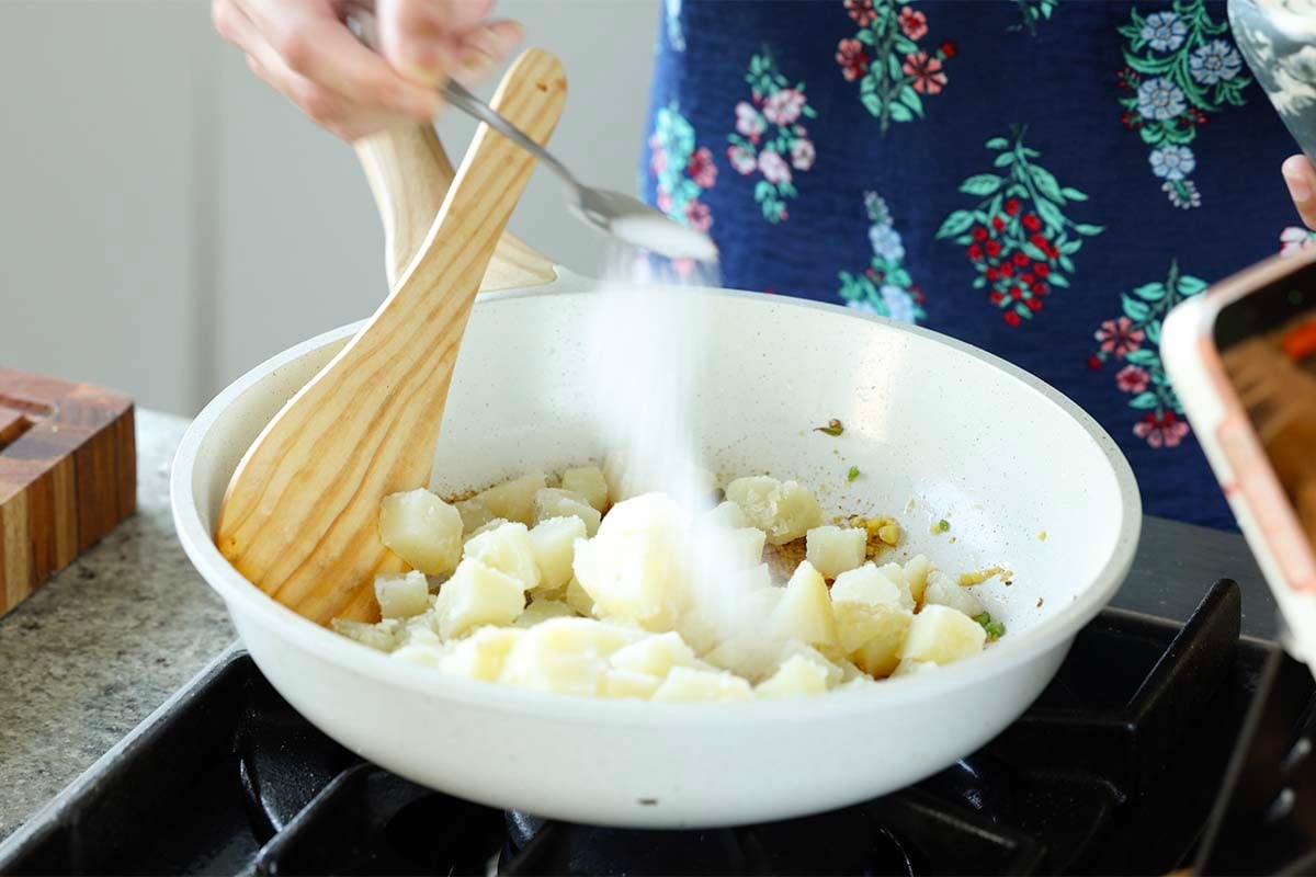 adding potatoes and salt to the pan