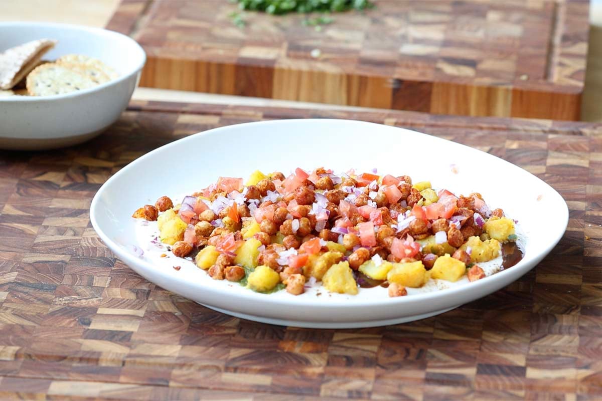 adding chickpeas, potatoes, tomato, and onion to the plate