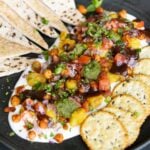 samosa platter with yogurt bed on a Black plate